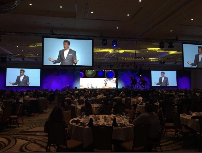 Nicholas Webb on stage in a packed ballroom