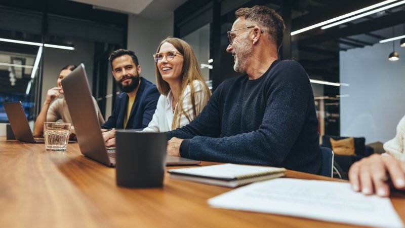 Successful group of businesspeople having a briefing in a boardroom. Happy businesspeople smiling while working together in a modern workplace. Diverse business colleagues collaborating on a project.