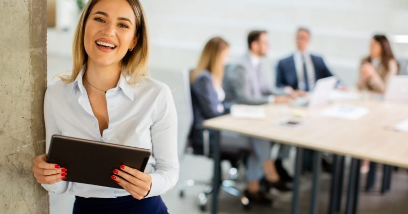 Young business woman standing with digital tablet in the office hallway
